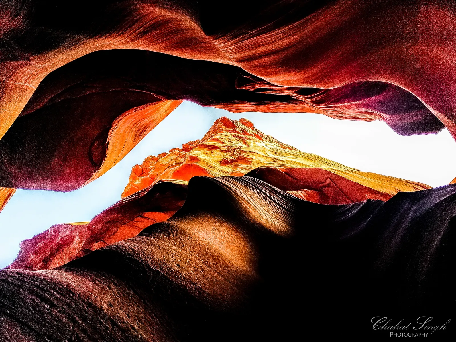Light beaming through a canyon opening, illuminating layered amber and rust-colored sandstone.