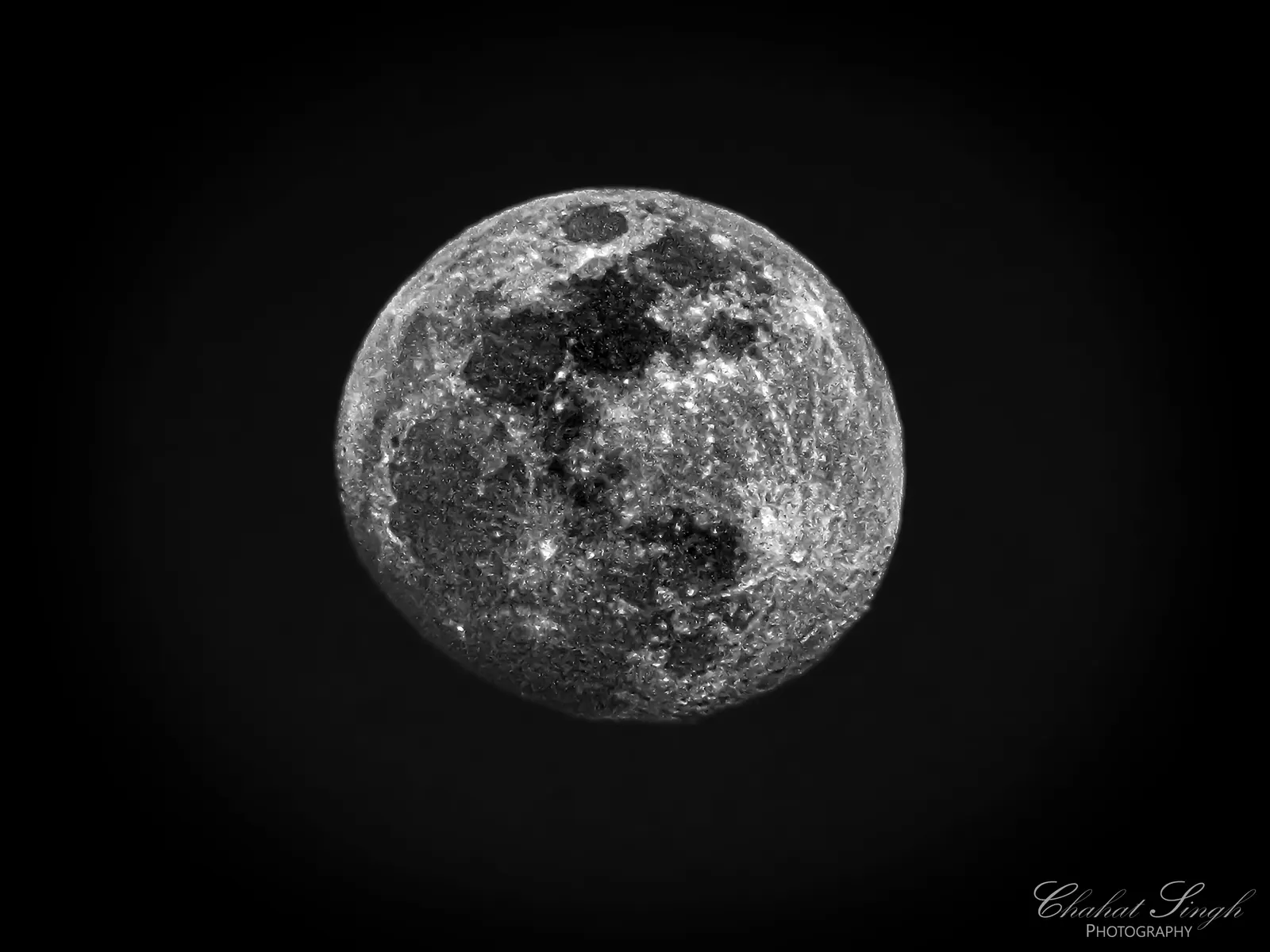 A close-up of the full moon, showing its cratered surface against a black sky.