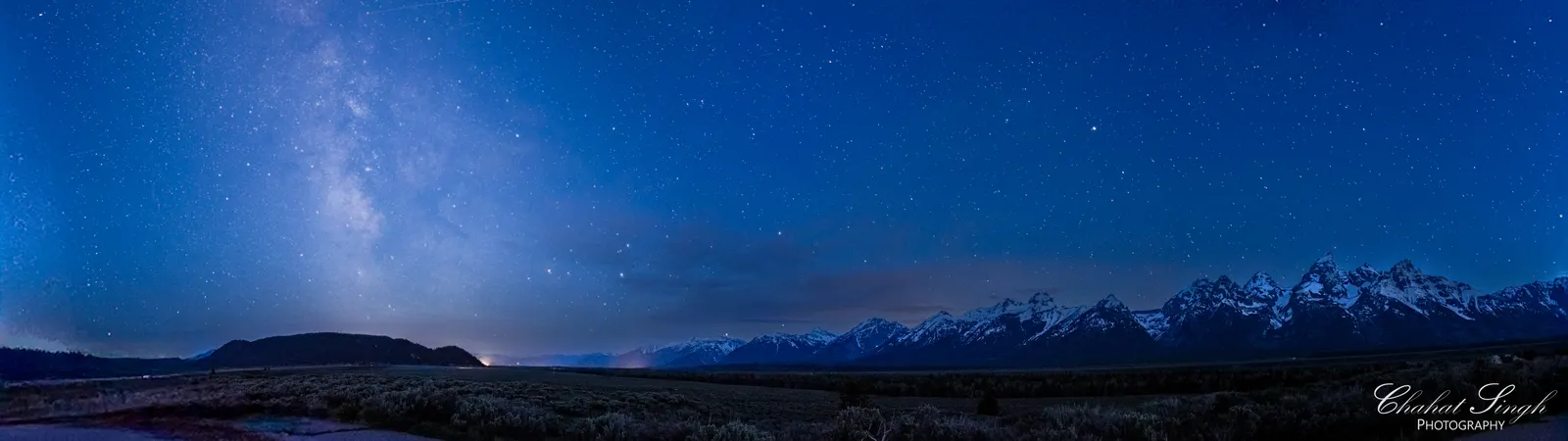 The Milky Way arching over the jagged peaks of the Grand Tetons at night.