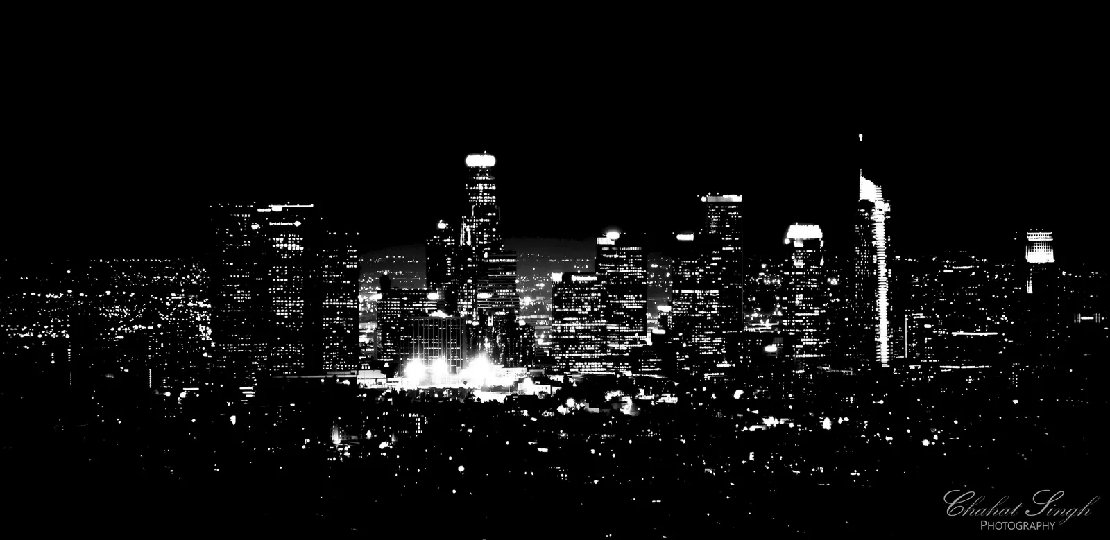 The Los Angeles skyline lit up at night, wide panoramic view in black and white.