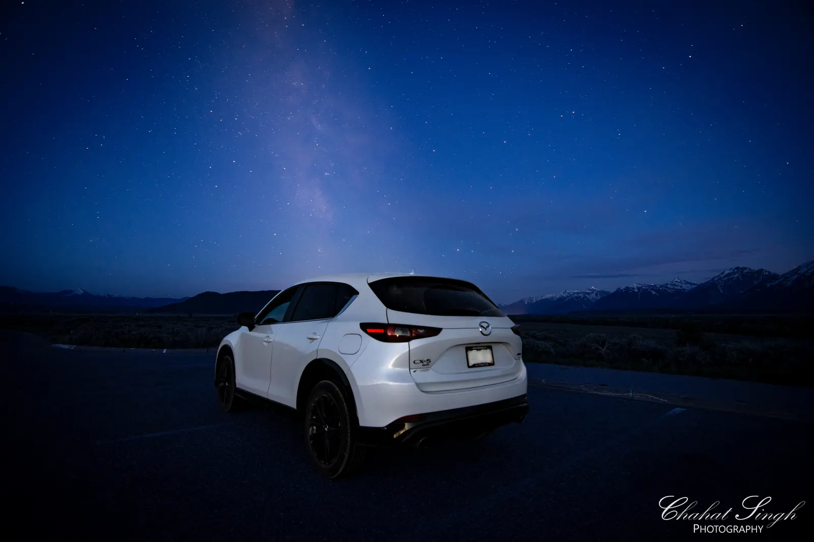 An SUV parked on a road beneath a star-filled sky with the Milky Way visible.